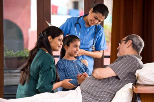 Female nurse and family with senior patient at home